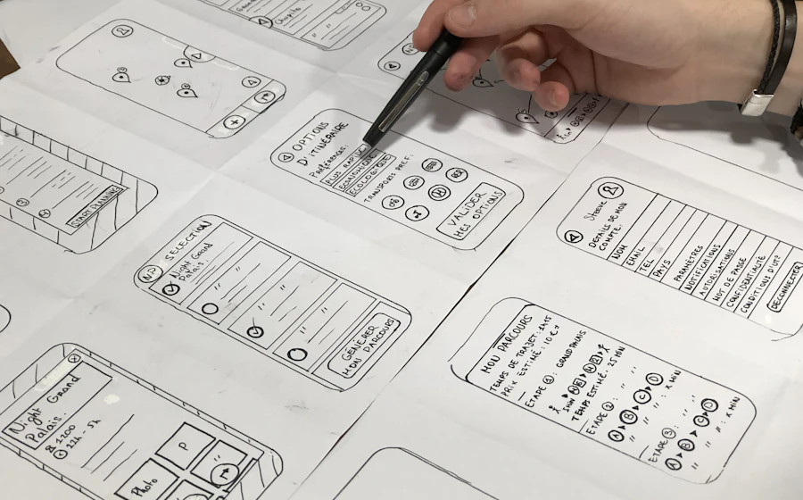 Designer sketching mobile app wireframes on paper